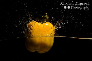Yellow Pepper dropping into water on black background 1