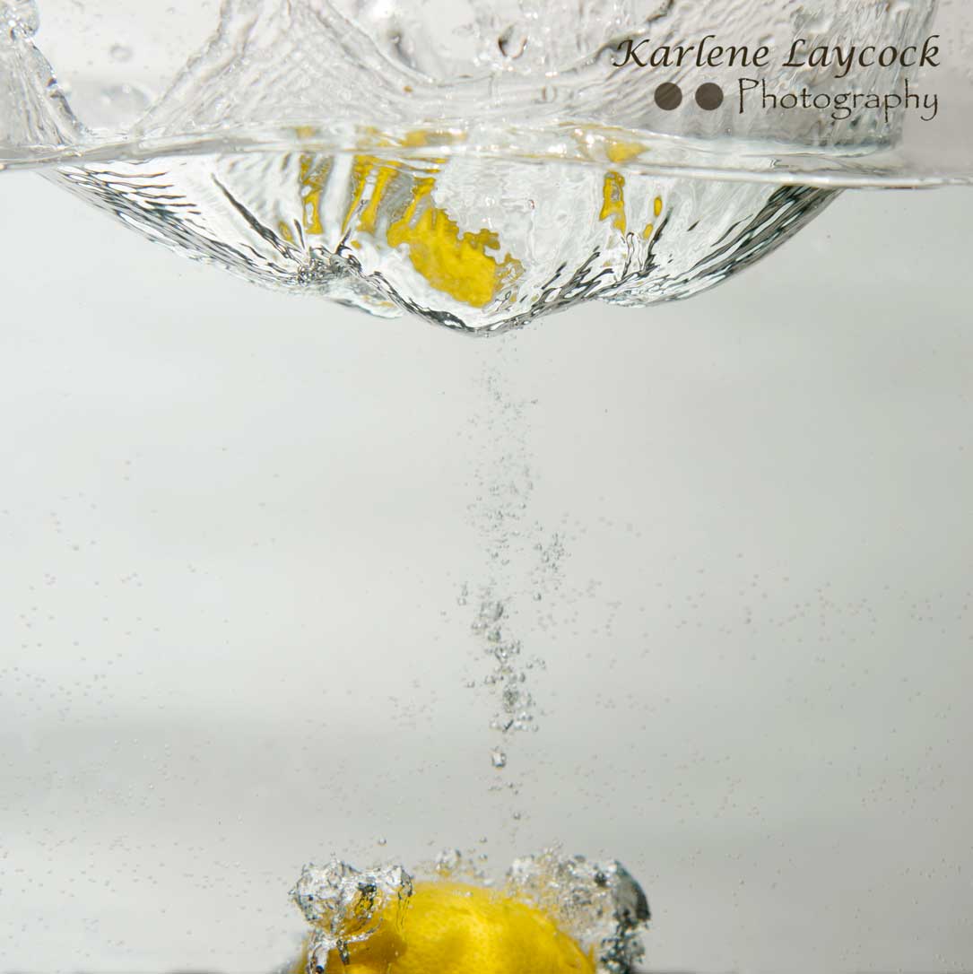 Lemon falling into water on grey 1