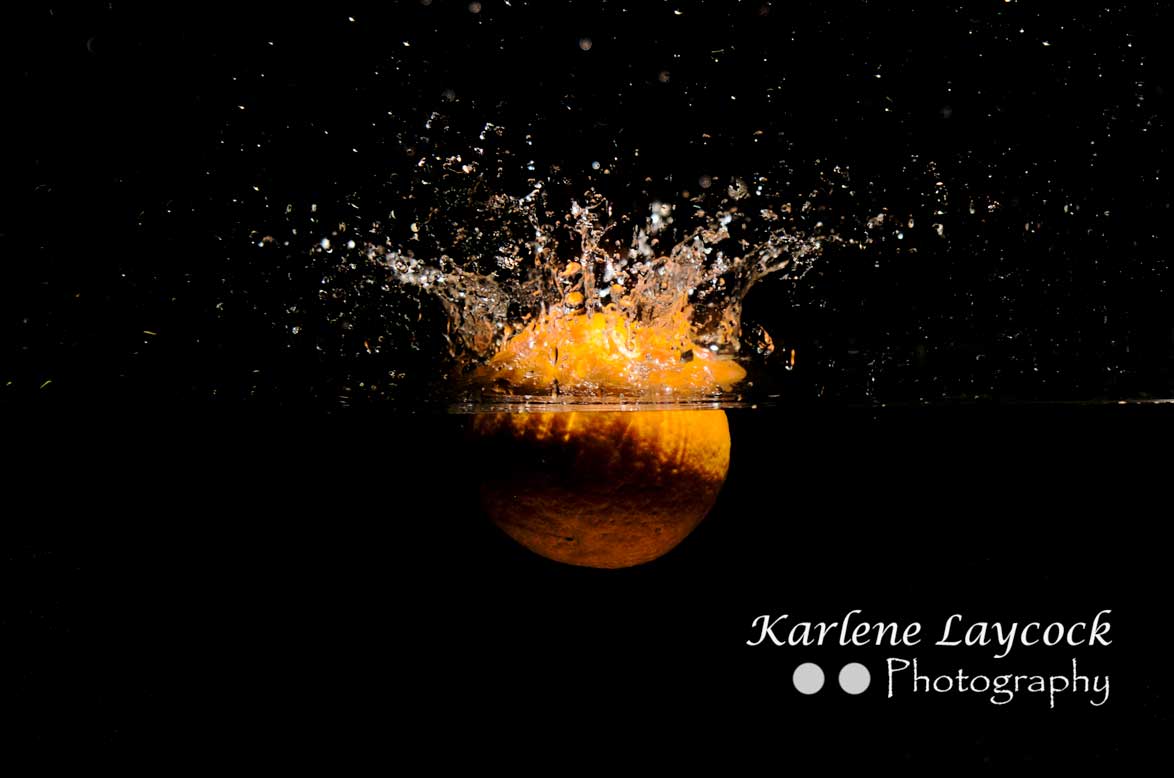 Orange dropping into water on black background 1