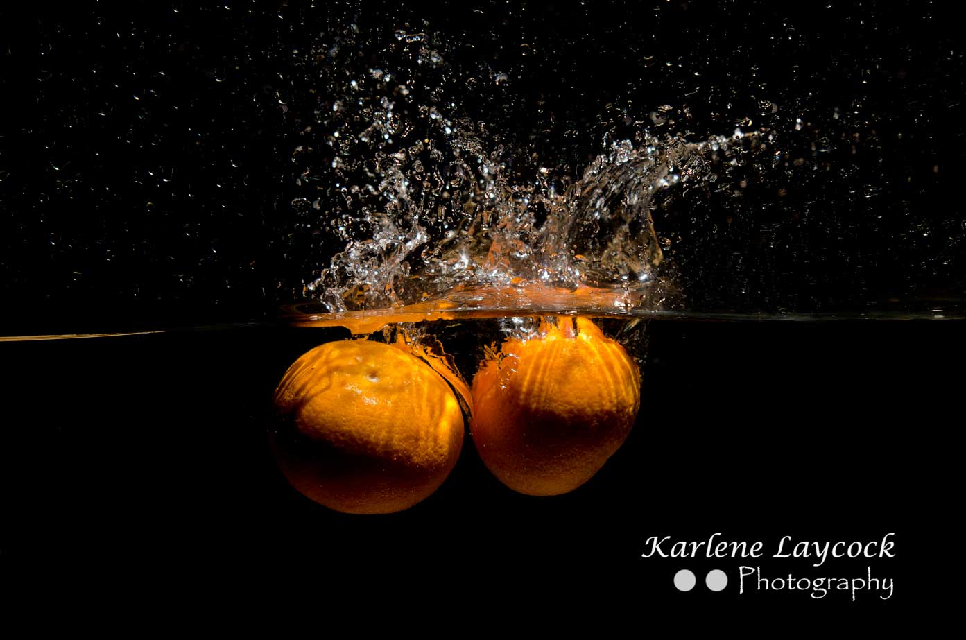 2 Orange dropping into water on black background 2
