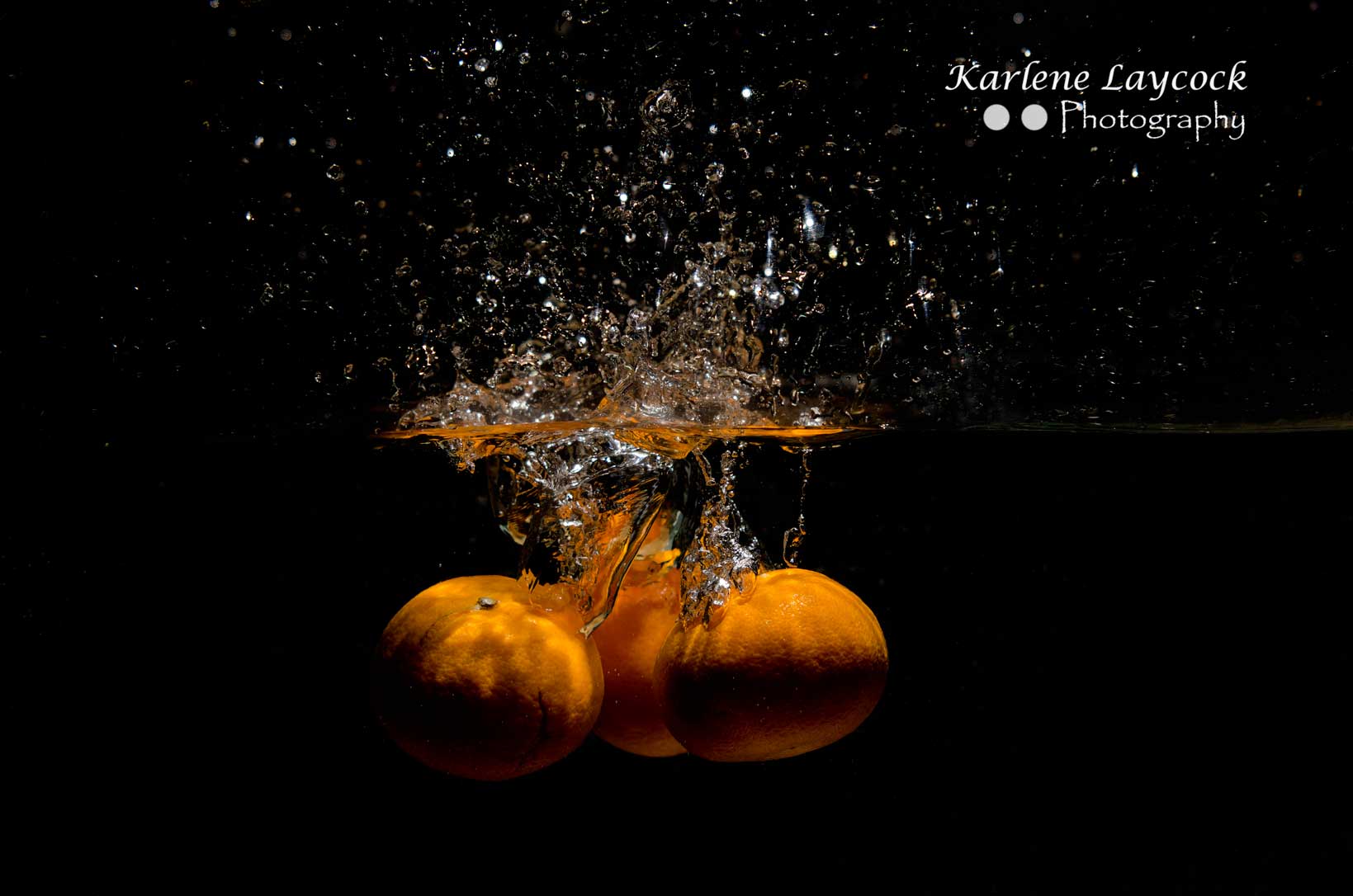 3 Orange dropping into water on black background 3