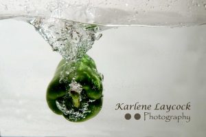 Green Pepper Submerged against a Grey Background with a Vortex Wave